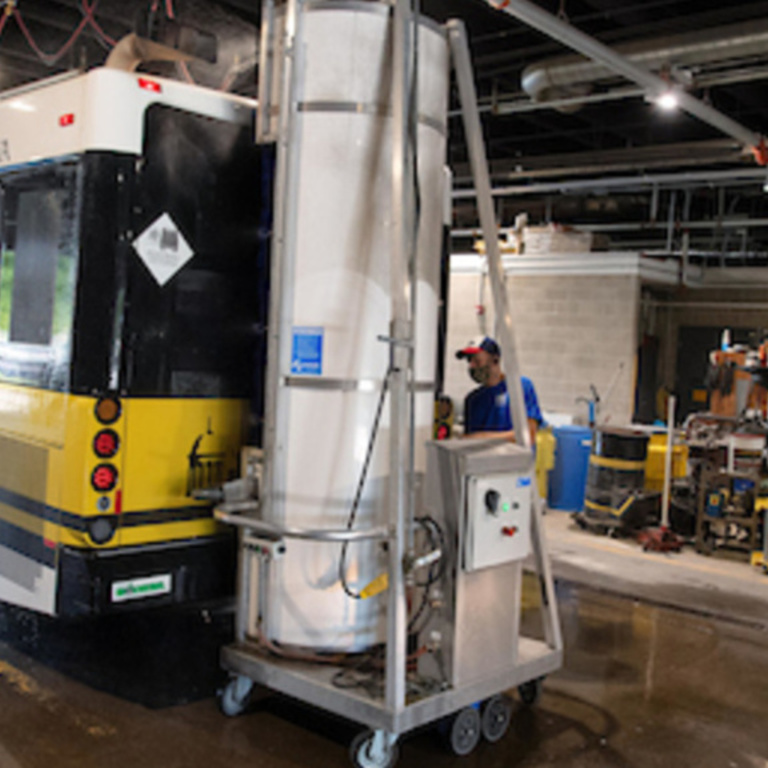 transit bus in black and gold color scheme being cleaned by machine and employee