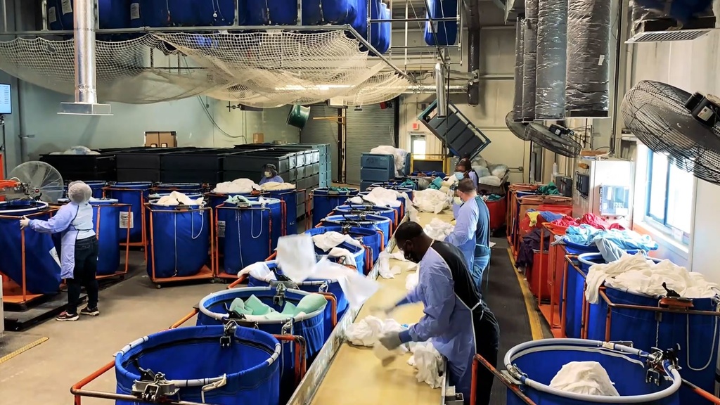 Image of persons sorting laundry wearing protective equipment