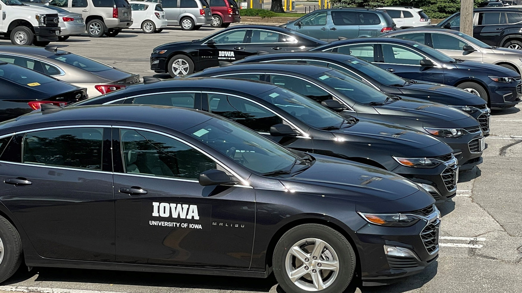 rows of vehicles parked with University of Iowa logo