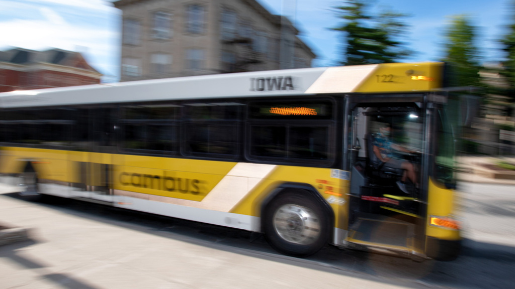 gold and black bus driving on campus during sunny summer day